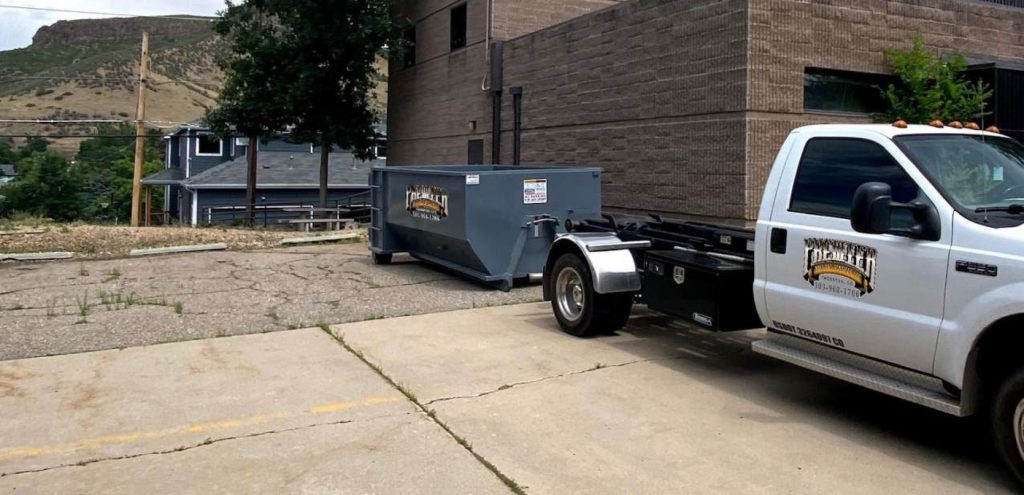 Driver placing commercial dumpster at Louisville, CO shopping center for retail renovation waste removal